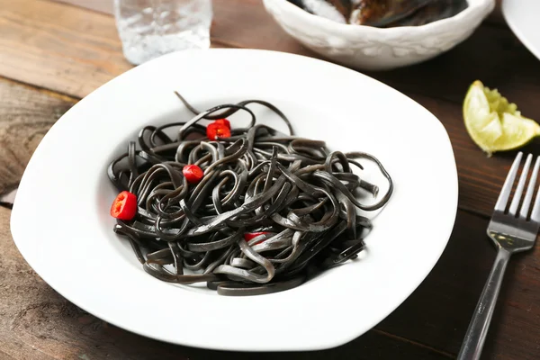 Cooked pasta and chili pepper on brown wooden background — Stock Photo, Image