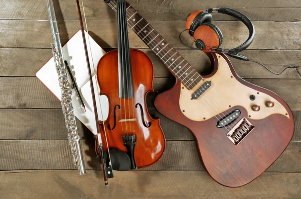 Ηλεκτρική κιθάρα, βιολί, σαξόφωνο σοπράνο, ακουστικά και βιβλίο σε ξύλινα φόντο — Φωτογραφία Αρχείου