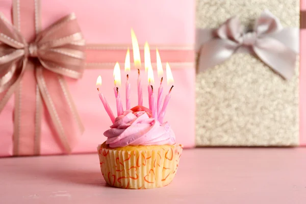 Dulce sabroso cupcake con velas en rosa presente cajas de fondo —  Fotos de Stock