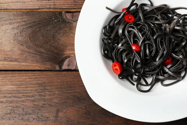 Cooked pasta and chili pepper on brown wooden background — Stock Photo, Image