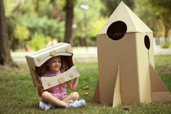 Девочка рядом с картонной ракетой — стоковое фото