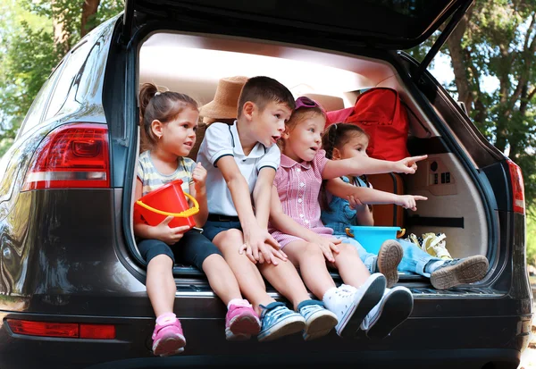 Happy children sit on car trunk — Stock Photo, Image
