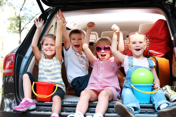 Les filles et les garçons assis sur le coffre de la voiture — Photo