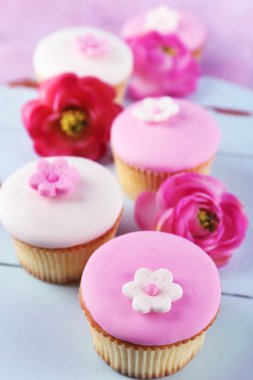 Lezzetli kek üzerinde çiçek ahşap arka plan ile colortasty cupcakes