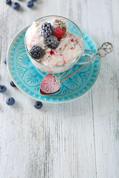 Delizioso gelato con bacche fresche congelate, su sfondo di legno a colori — Foto Stock