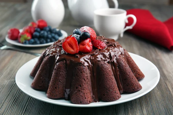 Delicioso bolo de chocolate com bagas em prato na mesa, close-up — Fotografia de Stock