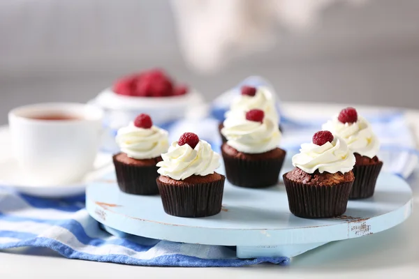 Mooie chocolade cupcakes met room en frambozen op tafel — Stockfoto