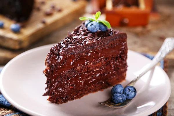 Bolo de chocolate com creme de chocolate e mirtilos frescos no prato, no fundo de madeira — Fotografia de Stock