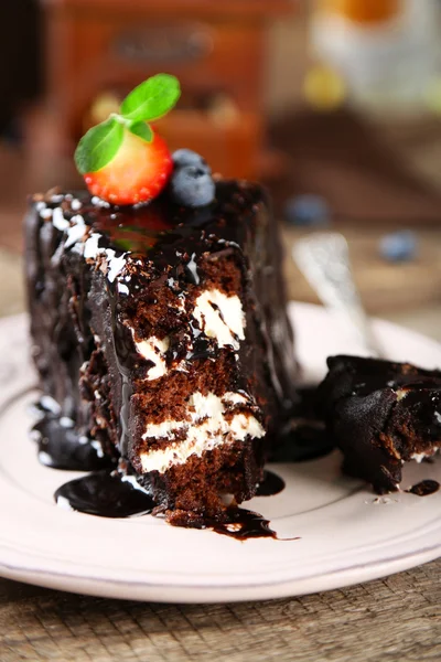 Chocolate cake with cream and fresh berries on plate, on wooden background — Stock Photo, Image