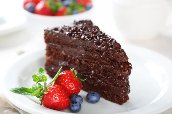 Chocolate cake with chocolate cream and fresh berries on plate, on light background — Stock Photo, Image