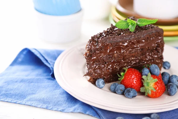 Chocolate cake met chocolade en verse bessen op plaat, op houten achtergrond — Stockfoto