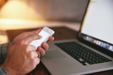 Genç adam onun telefon ve dizüstü bilgisayar kullanarak yakın çekim