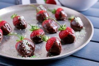 Çilek çikolata Mavi ahşap zemin üzerine bir tabak