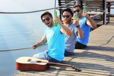 İskelede oturup ve birbirleriyle konuşmak genç erkekler