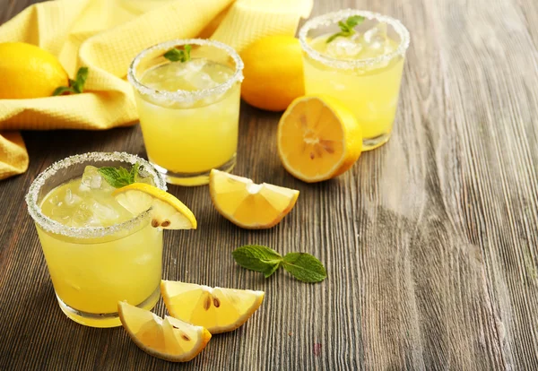Glasses of lemon juice on wooden table, closeup — Stock Photo, Image