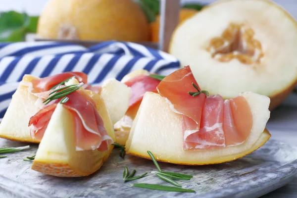 Melon with prosciutto of Parma ham on wooden table, closeup — Stock Photo, Image