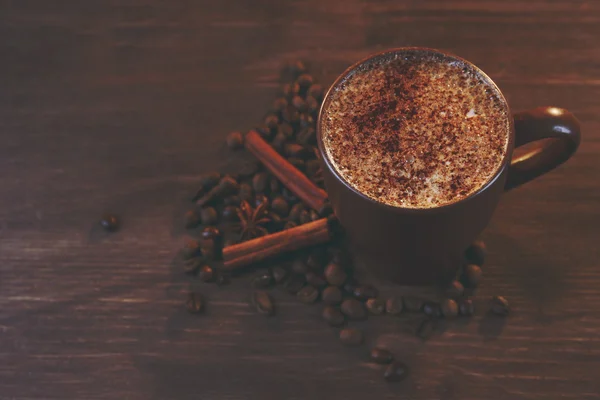 Leckeren heißen Kaffee mit gerösteten Bohnen und Zimt herum auf Holz Hintergrund — Stockfoto