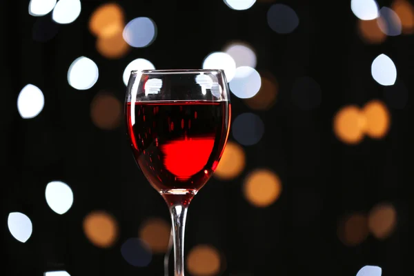 Copo de vinho na mesa de madeira contra luzes desfocadas fundo — Fotografia de Stock