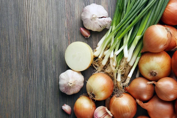 Cebollas frescas diferentes con ajo sobre fondo de madera — Foto de Stock