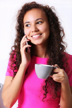 Fincan kahve ile cellphone tarafından konuşma pembe elbiseli genç kadın portresi kapatın