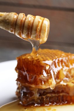 Ahşap arka plan üzerinde plaka üzerinde peteğin damlayan bal