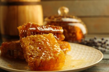 Peteğin plaka, bal ve ahşap arka plan üzerinde ahşap varil ile pota