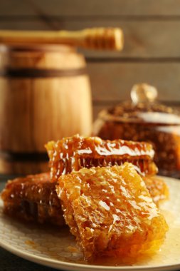 Peteğin plaka, bal ve ahşap arka plan üzerinde ahşap varil ile pota