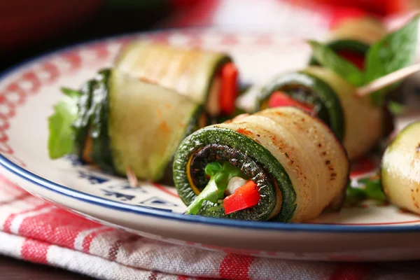 Rollos de calabacín con queso, pimientos y rúcula en el plato, primer plano — Foto de Stock