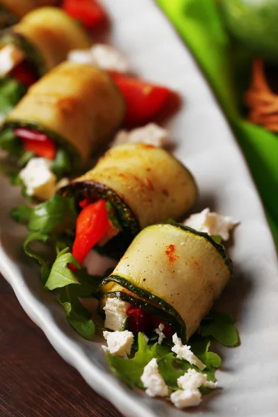 Zucchini rolls with cheese, bell peppers and arugula on plate, close-up — Stock Photo, Image