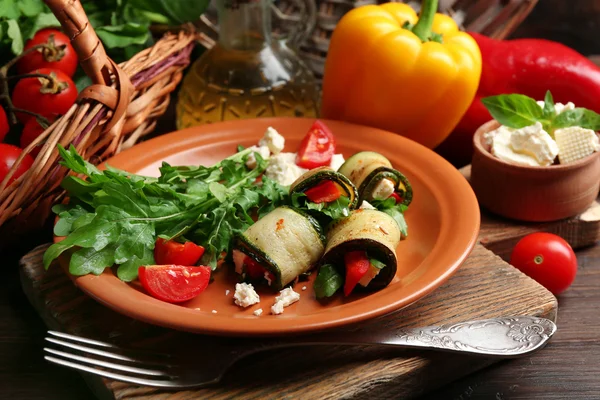 Rollos de calabacín con queso, pimientos y rúcula en el plato, primer plano, sobre fondo de mesa — Foto de Stock