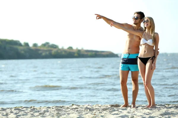 Pareja feliz apuntando a la playa — Foto de Stock