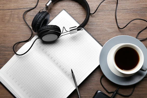 Hoofdtelefoon met papieren en kopje koffie op houten tafel — Stockfoto