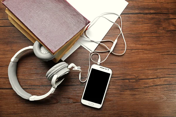 Hoofdtelefoon met oud boek en smartphone op houten tafel — Stockfoto