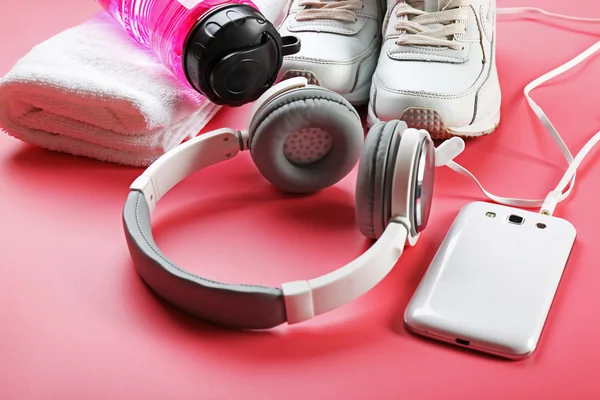 Hoofdtelefoon en sportuitrusting op roze achtergrond — Stockfoto