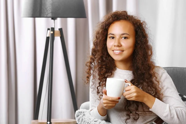 Joven hermosa mujer bebiendo café en el sofá en la habitación — Foto de Stock