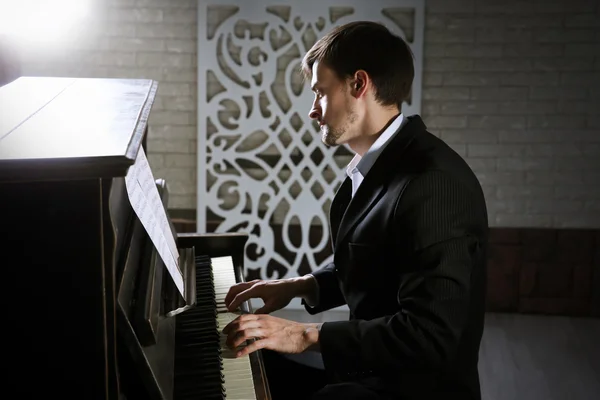 Homem de terno preto toca piano — Fotografia de Stock