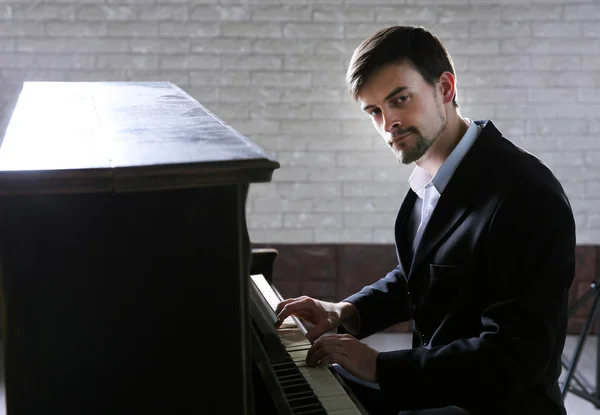 Homem de terno preto toca piano — Fotografia de Stock