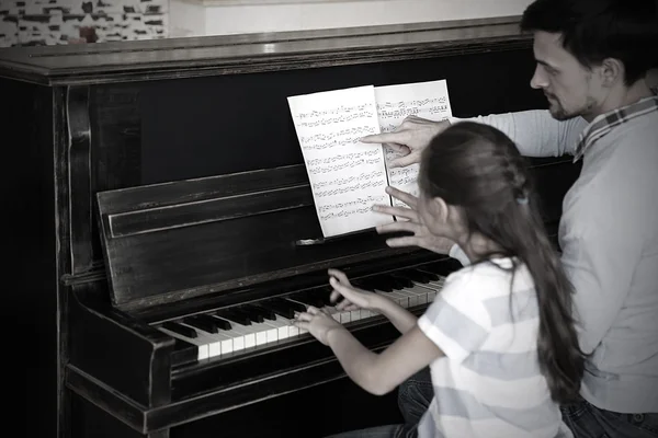 Lärare och flicka spela piano — Stockfoto
