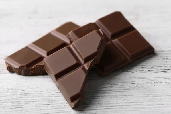 Pedaços de chocolate preto na cor de fundo de madeira — Fotografia de Stock