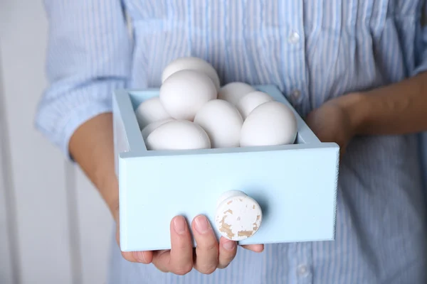 Uova in cesto nelle mani delle donne su sfondo di legno — Foto Stock