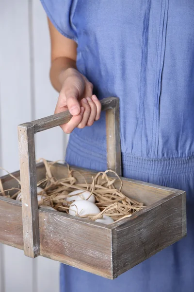 Eggs in basket in women hands on wooden background — Stock Photo, Image