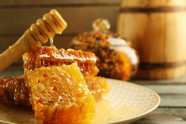 Petos de abeja y cazo de madera en placa sobre fondo de madera — Foto de Stock