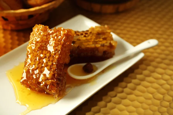 Honeycoms y cuchara en el plato sobre fondo brillante — Foto de Stock