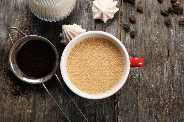 Чашка кофе с конфетами на деревянном фоне — стоковое фото