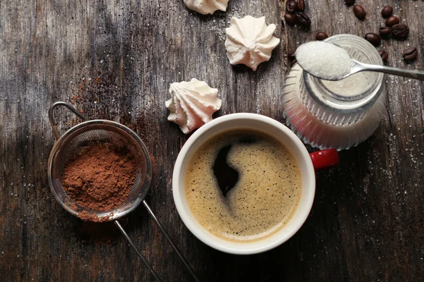 Чашка кофе с конфетами на деревянном фоне — стоковое фото