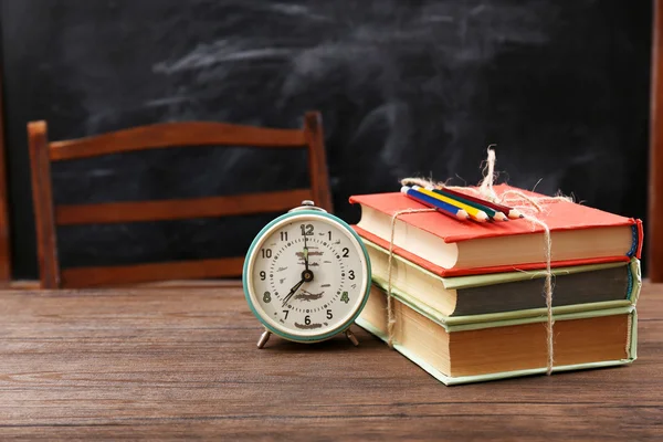 Kleurrijke stapel boeken met klok op houten tafel — Stockfoto