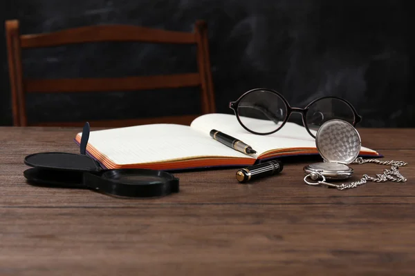 Άνοιξε το σημειωματάριο με γυαλιά και μεγεθυντικό φακό σε ξύλινο τραπέζι — Φωτογραφία Αρχείου