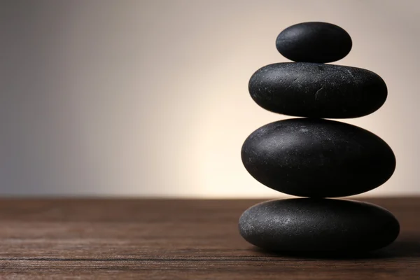 Black pebbles on wooden table — Stock Photo, Image