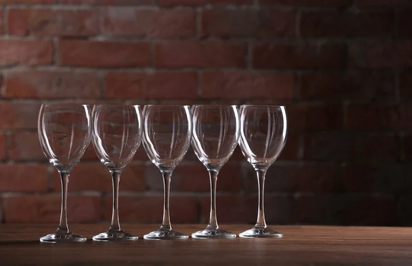 Empty wine glasses on a table on a brick wall background — Stock Photo, Image