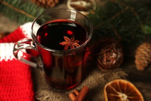 Christmas composition of mulled wine, cinnamon, pine and red knitted mittens on wooden background — Stock Photo, Image